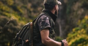 Man with hiking gear explores lush forest landscape, embodying adventure and nature.
